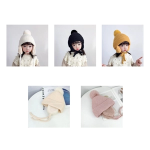 Detail view of colorful knit hats for children with earflaps and pompom decorations