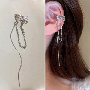 Gros plan d'un ear cuff nœud argenté avec franges et cristal porté sur l'oreille
