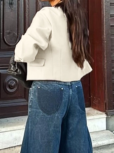 Back view of a casual beige short vest jacket paired with wide-leg blue jeans outdoors