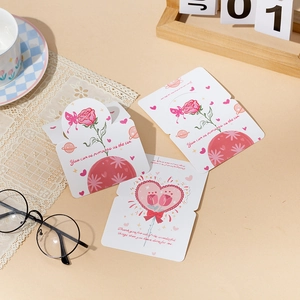 Flat lay of pink rose greeting cards with romantic quotes on a warm tabletop setting
