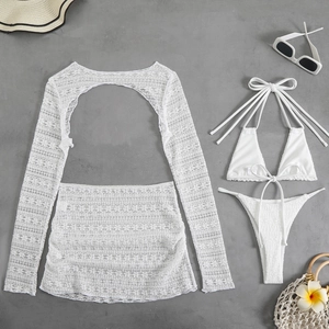 Flat lay of a white lace 4-piece beach set including a cover-up, skirt, and bikini