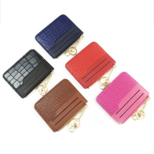 Flat lay of multiple colorful faux crocodile leather mini wallets with metal keychains