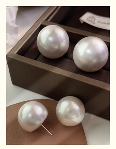 Macro shot of oversized white pearls with mirror luster and S925 silver studs on leather