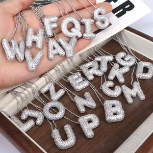 Macro shot of silver letter necklaces with iced-out cubic zirconia pavé detailing