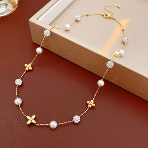 Detail of gold plated floral necklace with white pearls and sparkling zircon spheres
