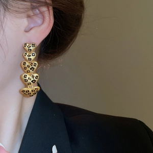 Nahaufnahme von herzförmigen Ohrringen mit Leopardenmuster und mattem Goldfinish