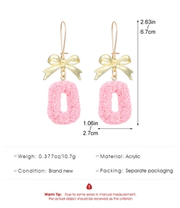 Detail view of pink letter O earrings with floral texture and golden bow hooks