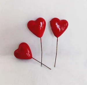 Macro shot of red glossy foam heart picks with brown wire stems for DIY floral crafts
