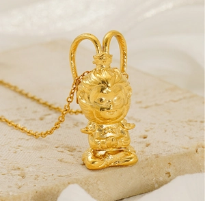 Macro shot of 3D Sun Wukong gold plated pendant necklace resting on textured stone