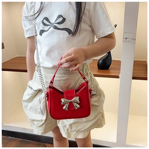 Close-up of red patent leather kids handbag with silver metal bow and fine chain strap