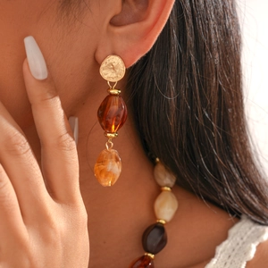 Close-up of a woman wearing retro amber acrylic beads with gold irregular metal earrings