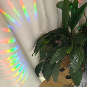 Rainbow light effect projected onto a white curtain from a hanging suncatcher prism