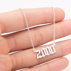 Close-up of a silver-toned year 2000 pendant on a polished stainless steel chain