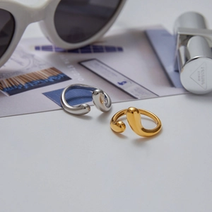 Minimalist gold and silver water drop open rings with liquid metal finish on a magazine