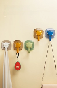Detail of five colorful adhesive wall hooks with gold trim and modern minimalist design