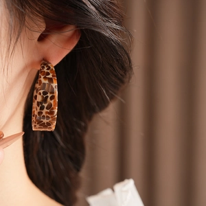 Close-up of tortoise shell leopard print resin C-shaped hoop earrings on model