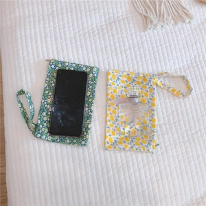 Detailed view of floral cotton mini pouches with wristlets next to a smartphone and perfume