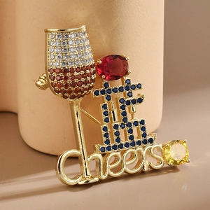 Macro view of gold wine glass brooch with zircon stones and Cheers letter detail