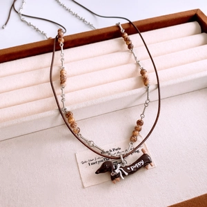Close-up of brown dachshund puppy pendant necklace with multi-layer beads and cord