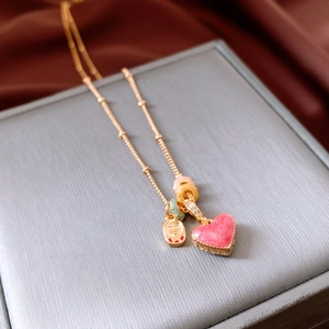 Detail of 18k gold heart pendant necklace with pink enamel and double happiness charm