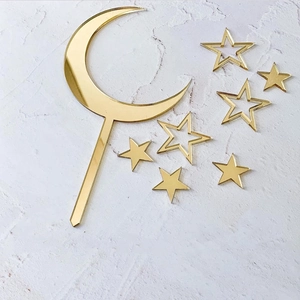 Gold acrylic cake toppers set with moon and stars on white marble background