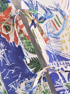 Detail of colorful tropical leaf print fabric and drawstring tie on the loose V-neck shirt