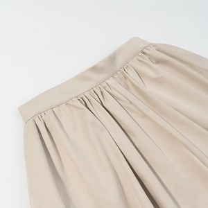 Detailed view of the elastic waistband and pleated texture of this beige mini skirt