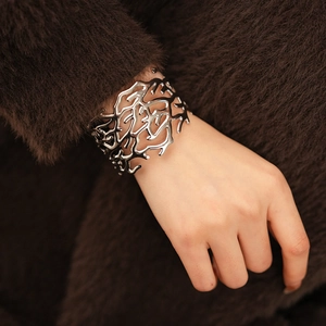 Detailed view of silver hollowed root pattern cuff bracelet worn on model wrist