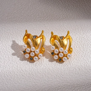 Dettaglio di orecchini vintage a foglia dorata con perle bianche e cristalli di zircone