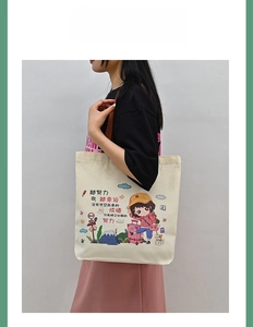 Detail of cream canvas tote bag with cartoon illustration and dark brown strap