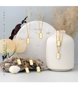 Detail view of gold-plated rectangular initial pendant necklaces with zircon micro-paving