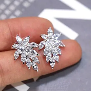 Hand holding silver leaf stud earrings featuring brilliant marquise cut cubic zirconia gems