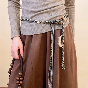 Handcrafted woven waist chain with wooden beads and tassels styled on a long skirt