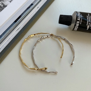 Minimalist wavy open cuff bracelets in gold and silver finish shown with lifestyle props