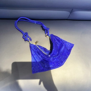 Detail of navy blue rhinestone hobo bag featuring a knotted shoulder strap and gold zipper