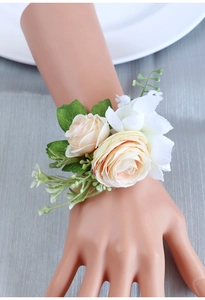 Detailed close-up of cream handmade bridesmaid wrist corsage with green berries