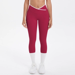 Détail de la taille croisée en V avec passepoil blanc sur un legging de yoga bordeaux