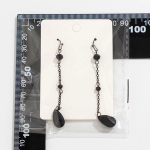Close-up of black beaded tassel earrings with faceted teardrop pendants on card