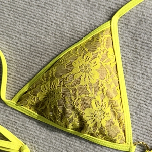 Detailed macro view of yellow floral lace bikini top with decorative gold metal ring