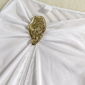 Detailed macro view of gold lava-style buckle on white mesh fabric bikini top