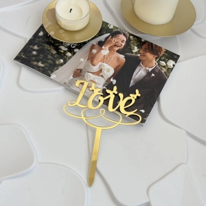 Close-up of golden acrylic Love cake topper with heart accent for wedding decor