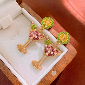 Macro shot of cocktail glass earrings with pink crystals and pearls on beige velvet
