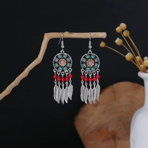 Macro detail of bohemian tassel earrings with floral enamel and vibrant beads