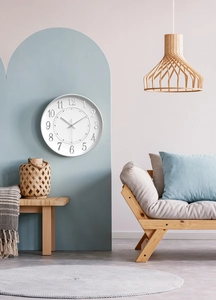 Close-up of minimalist white wall clock featuring embossed numerals and silver hands