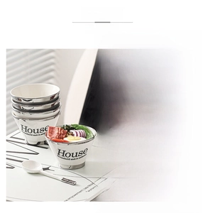 Detail of silver-rimmed white ceramic soup bowl with spoon and House text engraving
