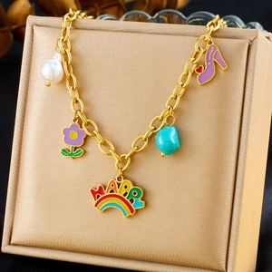 Detailed view of golden charm bracelet with rainbow, pearl, and turquoise on jewelry box