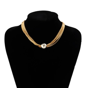 Close-up of a layered gold chain necklace with a silver ball pendant on a black bust
