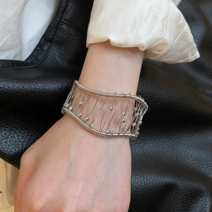 Close-up of a wide silver woven mesh cuff bracelet with intricate bead detailing