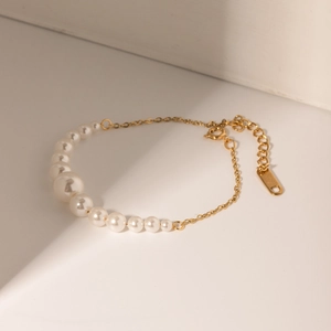 Detail of 18k gold-plated chain bracelet featuring graduated white pearls and adjustable clasp
