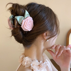 Gros plan d'une pince à cheveux rose en tissu avec feuilles en soie dans un chignon